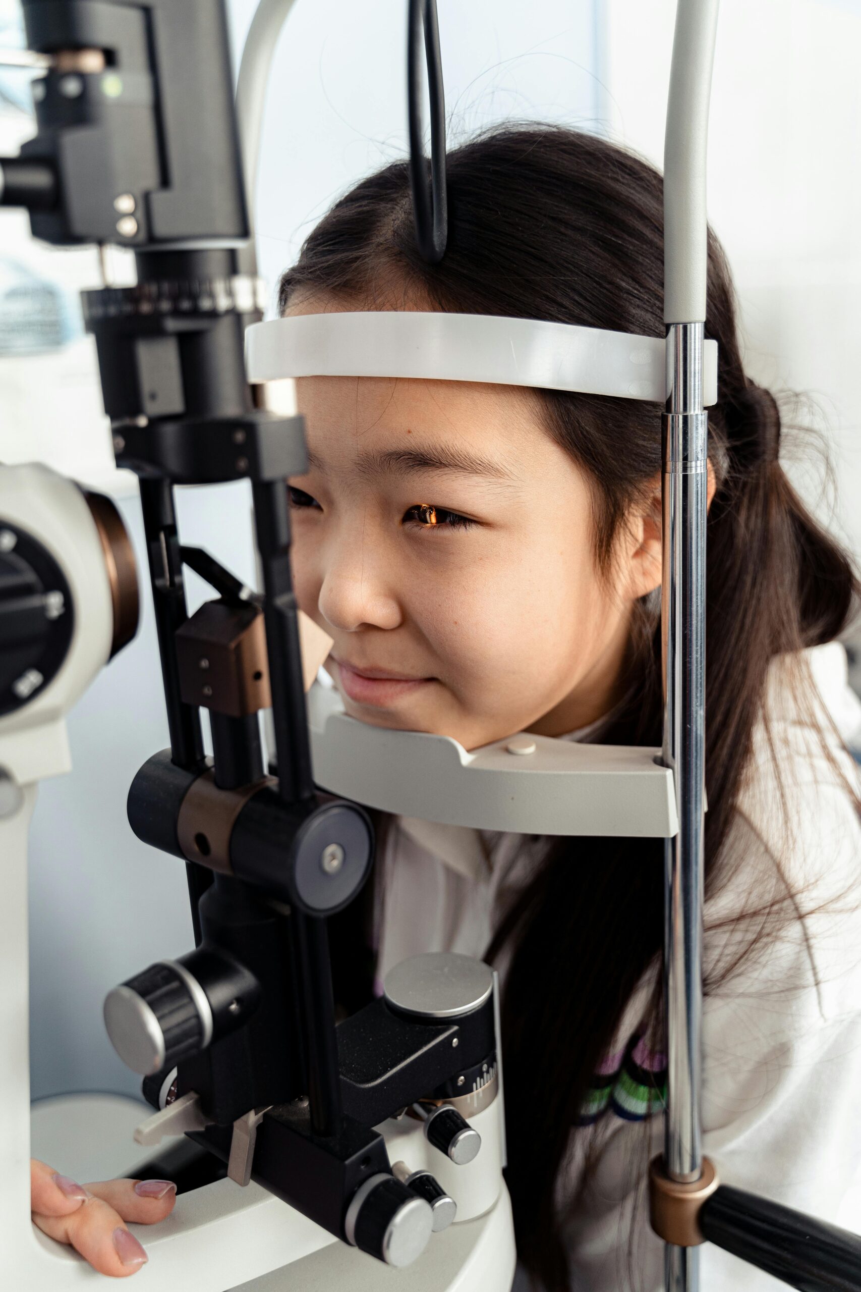 A teenage girl experiencing an optometry check-up indoors using advanced medical machinery.